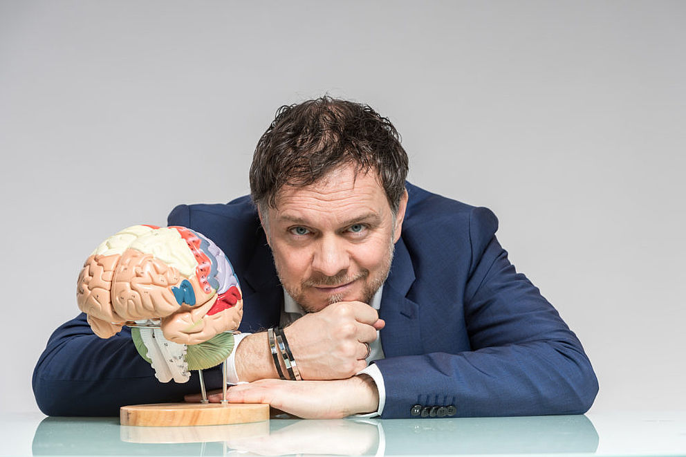 Prof. Dr. Volker Busch vor einem Gehirnmodell